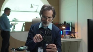 Olgun profesyonel insan mühendisinin portresi tornavida kullanarak protez kol geliştiriyor. Fütüristik ofisteki IT şirketinde çalışan zeki ve yaşlı bir teknisyen..