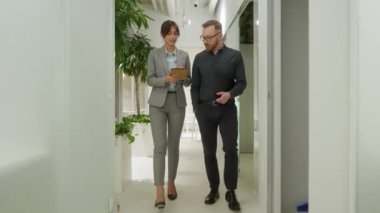 Modern şirkette çalışan başarılı bir yetişkinle ofiste yürüyen şık bir kadının portresi. Tablete bakan iki güzel iş arkadaşı şık kıyafetler giyiyor..