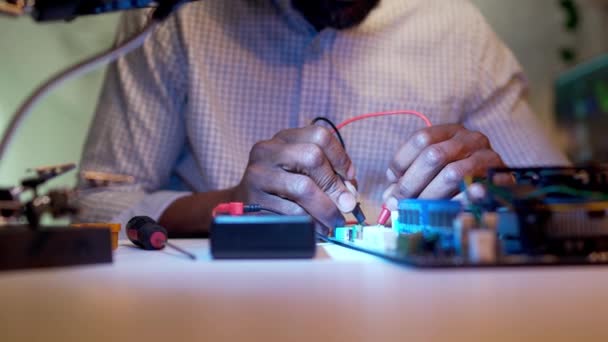 年轻的专业非洲裔美国工程师用测试仪对计算机部件进行诊断的特写 专注于使用办公工具修理主板的成功人士 — 图库视频影像