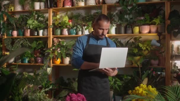 Portret Młodego Atrakcyjnego Mężczyzny Trzymającego Laptopa Pracującego Online Kwiaciarni Jako — Wideo stockowe