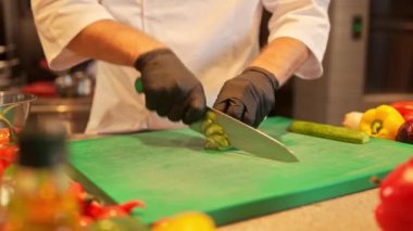 Profesyonel yetenekli erkek şeflerin salatalık kesme tahtasında salatalık keserken yakın çekim görüntüsü. Çok çalışkan Kafkas aşçısı lezzetli yemekler pişirmeden önce malzemeleri hazırlıyor..