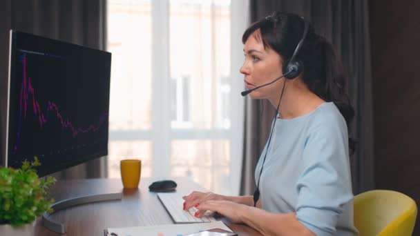 Επιχειρηματίας Μιλάει Ακουστικά Για Την Εργασία Διαγράμματα Αρκετά Καυκάσια Γυναίκα — Αρχείο Βίντεο