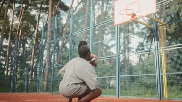回望非裔美国人慈爱的父母举起他的孩子扔一个球在篮筐里 儿子和父亲在城外的公园打篮球 休闲的概念 从下往下男孩抛球而失手 — 图库视频影像