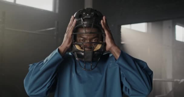 非洲裔美式足球运动员在暗室训练后摘下头盔的肖像 英俊的男人蓄着胡子 凶狠地看着摄像机 体育竞赛的概念 — 图库视频影像