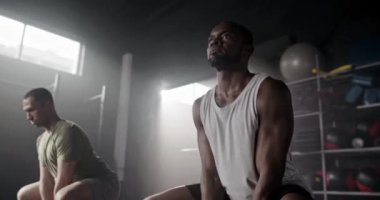 Yakışıklı Afro-Amerikan güçlü adamlar gölge fitness kulübünde spor aletleriyle çömeliyorlar. Çekici erkekler vücut çalışıyor, kardiyo egzersizleri yapıyor. Arkadaşlar sağlığa ve vücuda önem verir..