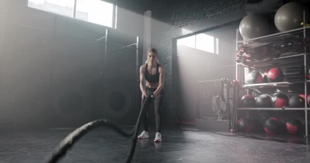 用运动服拉着绳子 一个人在黑暗的健身俱乐部里做运动的白人肌肉女人 漂亮的女性专注于训练过程 体操概念 — 图库视频影像