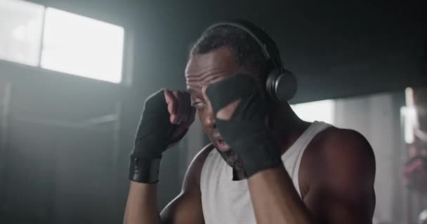 Knappe Afro Amerikaanse Bokser Met Elastische Bandages Bokszak Donkere Sportschool — Stockvideo