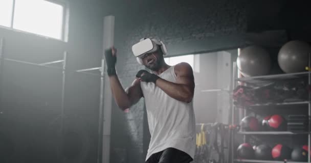 英俊的非洲裔美国拳击运动员在健身俱乐部接受虚拟现实的训练 迷人的男人穿着运动服 头戴Vr耳机 与想象中的对手打斗 未来的技术概念 — 图库视频影像