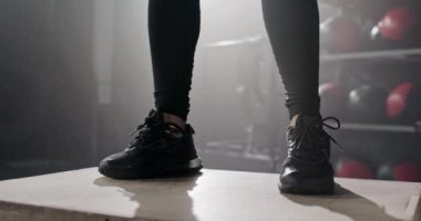 Spor ayakkabılı, spor ayakkabılı, spor ayakkabılı, gölgeli spor salonunda yüksek atlama yapan bir kadın. Daha kolay eğitim için ayakkabıları kapatın. Spor kıyafetleri ve kıyafet kavramı.