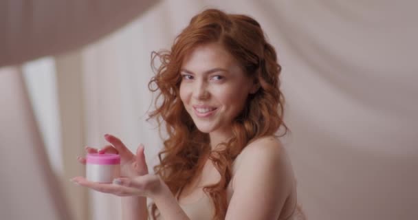 用化妆品站在相机前的卷曲造型肖像 丝织品在背景中摇曳 拥有天然美丽乳液 面膜或乳霜的女人 广告化妆品概念 — 图库视频影像