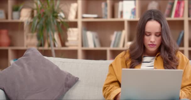 かなり白人女性が家でソファに座っている ノートパソコンや遠隔操作で勉強する魅力的な使い古された女性 仕事を終えた後 喜んで笑顔と疲れデジタルデバイスをオフにします — ストック動画