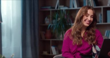 Genç beyaz kadın videosu arıyor ve internette sohbet ediyor. Tablet bilgisayar kullanan sevimli bir kadın kütüphanede oturuyor ve kameraya gülümsüyor. Neşeli iletişim, keyifli ruh hali.