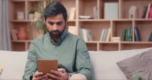 Όμορφος Άντρας Γενειάδα Κάθεται Στη Βιβλιοθήκη Κρατώντας Tablet Υπολογιστή Πατώντας — Αρχείο Βίντεο