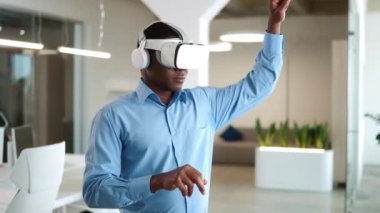 Ofiste sanal gerçeklik kulaklığı takan Afrikalı Amerikalı işçi. İş dünyası için ekonomik ya da finansal modelleme uzmanı. Teknoloji aygıtı ile projeleri yönetmek veya pazarlamak.