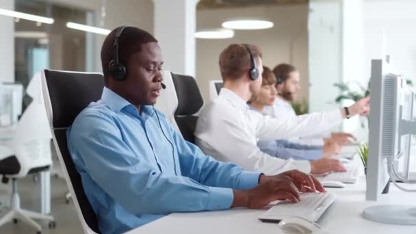 忙碌的多族裔经理使用耳机和与客户沟通 在金融业工作的人 使用个人计算机 点击键盘 经济工业的概念 — 图库视频影像