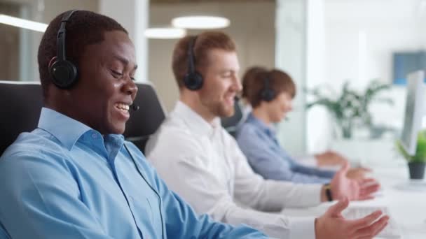 一个积极的混合种族的经理团队 戴着耳机 愉快地咨询客户 在电脑上工作时 开心地微笑或大笑 呼叫中心的概念或支持服务 — 图库视频影像