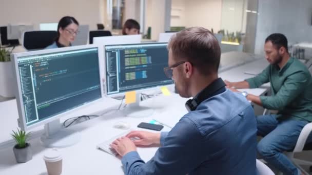 努力工作的混合种族开发人员一起在现代办公室的计算机上工作 忙着为用户创建和开发软件的人 屏幕上可见的图表和编程代码 — 图库视频影像
