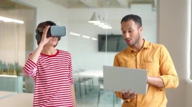 İki çok ırklı mühendis yenilik teknolojisini test ediyor. Akıllı adam bilgisayarını kullanırken sanal gerçeklik kulaklığı olan çalışkan bir kadın etrafa bakıyor. Simülatör sistemini geliştiren insanlar.