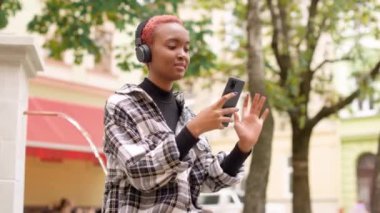 Akıllı telefon ekranına bakıp kulaklıkla müzik dinleyen mutlu genç bir kadının portresi. Oldukça şık bir bayan kulaklıkla dışarıda cep telefonu kullanarak şarkı söylüyor. Boş zaman konsepti