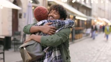 Mutlu melez genç çiftler uzun bir ayrılıktan sonra sokakta buluşup sarılıyorlar. Zevkli bir erkek kız arkadaşını ya da arkadaşını kucaklıyor ve gülümsüyor. Keyfin yerinde. Arkadaşlık kavramı