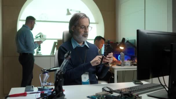 放大白人胡子科学家创造机器人手在实验室 忙碌的男人坐在电脑前 紧紧围绕着技术目标的螺丝 现代技术的概念 — 图库视频影像