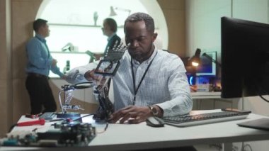 Laboratuvarda robotik el yapan Afrikalı Amerikalı müteahhit. Mühendislik icadı üzerinde çalışan çalışkan bir adam. Yaratıcının arkasında iki iş arkadaşı aktif olarak konuşuyor. Yüksek teknoloji kavramı, yenilik.