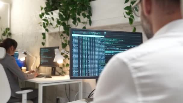 在计算机上对忙碌的男性程序员编码和编程软件的后视镜 在电脑上监视可见的海量数据 在现代办公室做程序代码的人 为客户创建网站 — 图库视频影像
