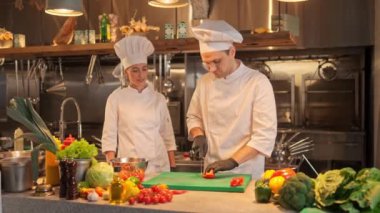 Kadın baş aşçı, erkek aşçıya lezzetli sebze yemekleri yapmayı öğretiyor. Profesyonel bir restoranda çalışırken kadın ve erkeğin iletişimi yemek pişirir..