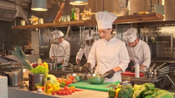 Femeia Gătește Îmbrăcată Uniformă Specială Mănuși Amestecă Frunzele Salată Legumele — Videoclip de stoc