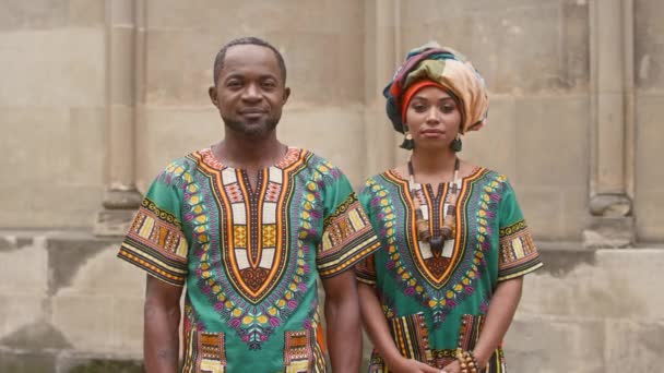 身着非洲传统服装的多文化夫妇 男男女女穿着华丽的服装 穿着鲜艳衣服的男男女女直接看着相机 戴珠宝和头巾的非洲妇女 — 图库视频影像