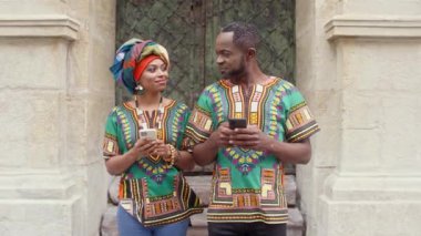 Geleneksel Afrika kıyafetleri içinde birbirine bakan bir çift. Sarıklı ve süslü elbiseli bir kadının telefonu. Çok ırklı bir adam telefonda gülümsüyor ve mesajlaşıyor. Mutlu Afrikalılar ellerinde aletlerle.