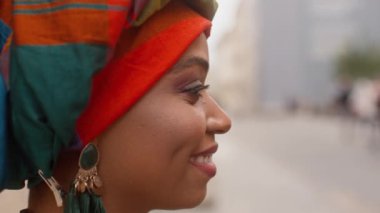 Yandan ateş et. Afrikalı kadın portresi. Sarıklı, gülümseyen bir kadın. Kafasına renkli eşarp takan neşeli kadınların yakın çekimi. Geleneksel mücevher ve sarılmış kafa içinde çok ırklı bir kadın..