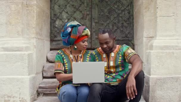 Afrikai Férfi Nevetnek Lépcsőn Többnemzetiségű Pár Hagyományos Ruhában Akik Laptopon — Stock videók