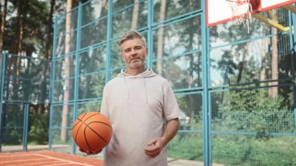 Портрет Улыбающегося Взрослого Мужчины Стоящего Открытой Баскетбольной Площадке Взрослый Баскетболист — стоковое видео