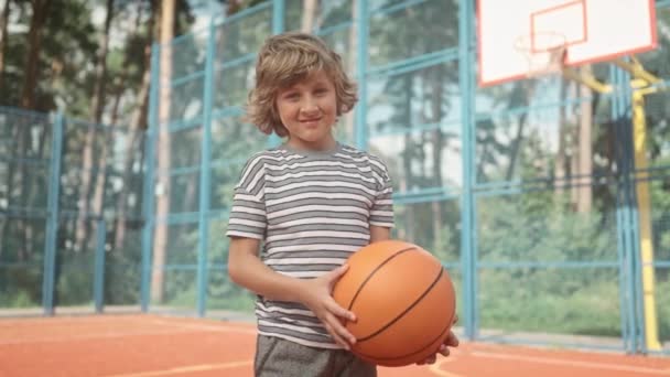 Πορτρέτο Του Μικρού Αγοριού Στέκεται Στο Γήπεδο Μπάσκετ Και Κρατώντας — Αρχείο Βίντεο