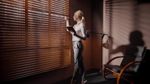 Приближается Белой Женщине Средних Лет Держащей Планшетное Устройство Подглядывающей Окно — стоковое видео