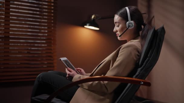 태블릿 장치에 그녀의 친구와 원격으로 통신하는 헤드셋을 코카서스 여성의 블라인드가있는 — 비디오