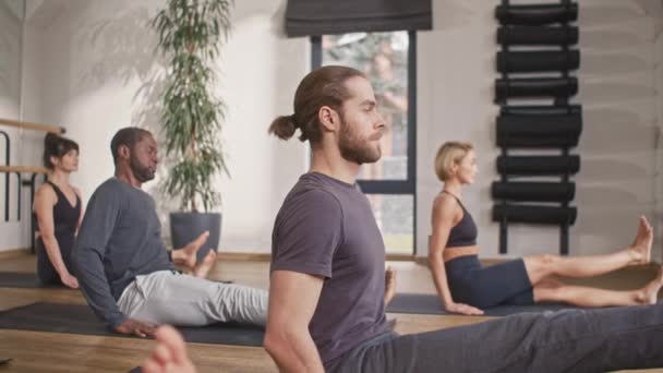 多民族团队坐在健康中心垫子上的侧视图 穿着运动服的人在练习冥想练习 跟随有氧运动跟随他们的教练 体育概念 — 图库视频影像