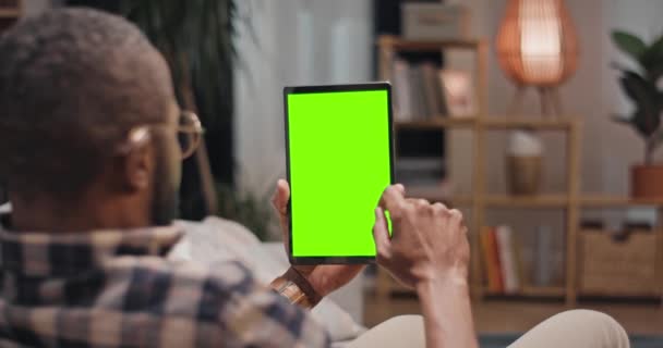 Afroamerikansk Man Sitter Vid Soffan Och Vidrör Den Gröna Tablettskärmen — Stockvideo
