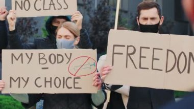Karantina karşıtı protesto. Kilitlenme ve sağlık politikalarına karşı gösteri yapan çok ırklı gençler, arka planda protesto yapan erkekler ve kadınlar, kağıt afişlere odaklandılar