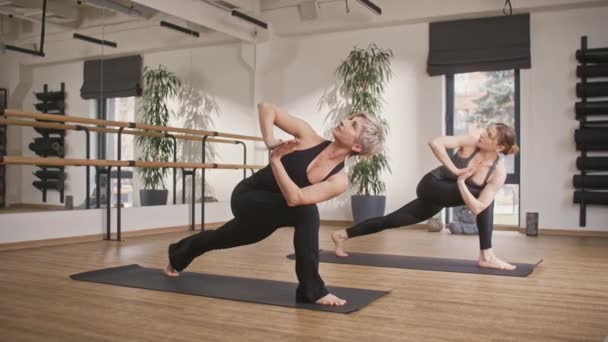 两名白人妇女在健身中心积极练习瑜伽 在体育锻炼期间穿着运动服的女性 把时间花在一起很有用 娱乐的概念 — 图库视频影像