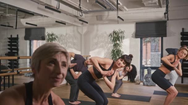 多国公司的人在健身室积极地做瑜伽 穿着运动服在垫子上做冥想练习 根据上司的指示同步重复动作 — 图库视频影像