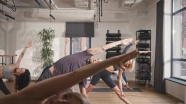Spor salonunda vücut esneme hareketleri yapan bir grup insan. Paspasların üzerinde durup vücut-vücut egzersizleri yapmak. Vücutlarının gençleşmesi ve kan dolaşımının iyileşmesi..