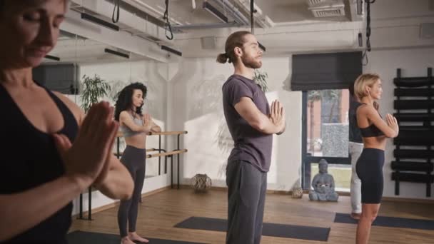 人们在健身室学习冥想的侧视图 年轻人在做瑜伽运动时穿着运动服站在垫子上 训练时深呼吸 改善精神健康 — 图库视频影像