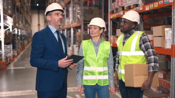 倉庫の従業員が男性マネージャーに報告する タブレットを持ち ロジスティック会社を検査するフォアマン ストック廊下で議論している多文化労働者 エスニック多様性 — ストック動画