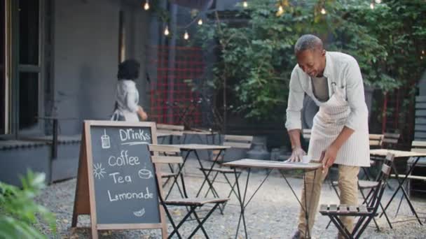 Ciężko Pracujący Afroamerykańscy Kelnerzy Fartuchach Czyszczący Brudne Stoły Tarasie Komunikowanie — Wideo stockowe