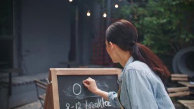 Beyaz önlüklü güzel bir kadın terasta dikilirken açık kelime yazıyor. Cafe ya da restoran açmadan önce neşeli garson kendini mutlu hissediyor. Müşteri kabul etmeyi bekliyor. Görev konsepti.
