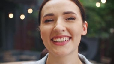 Kameraya bakarken neşeyle gülümseyen beyaz kadın portresi. İyimser genç bir kızın sokakta dururken iyi hisleri var. İfade. Doğal güzellik konsepti.