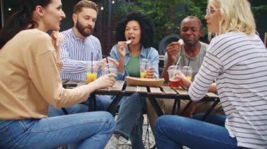 Restoranda ya da terastaki sokak barında dinlenen melez arkadaşlar. Gençler meyve suyu ya da limonata içerken birbirleriyle konuşuyorlar. Bir grup insan birlikte yemek yiyor ve eğleniyor..