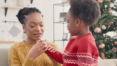 Sevgili Afrikalı Amerikalı anne küçük tatlı kızını sayarak öğretmenlik yapıyor. Evde matematik öğrenirken birlikte neşeyle gülümsüyoruz. Arka planda görünen Noel ağacı. Evde eğitim kavramı.